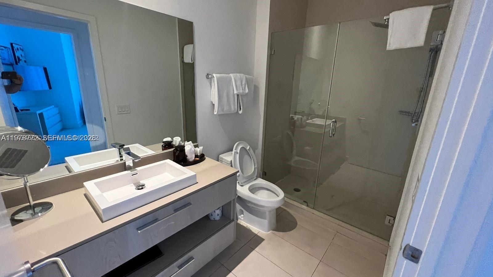 A modern bathroom features a floating vanity with a rectangular sink, toilet, and glass-enclosed shower — 4111 S Ocean Dr # 302, Hollywood FL 33019, HOLLYWOOD, FL