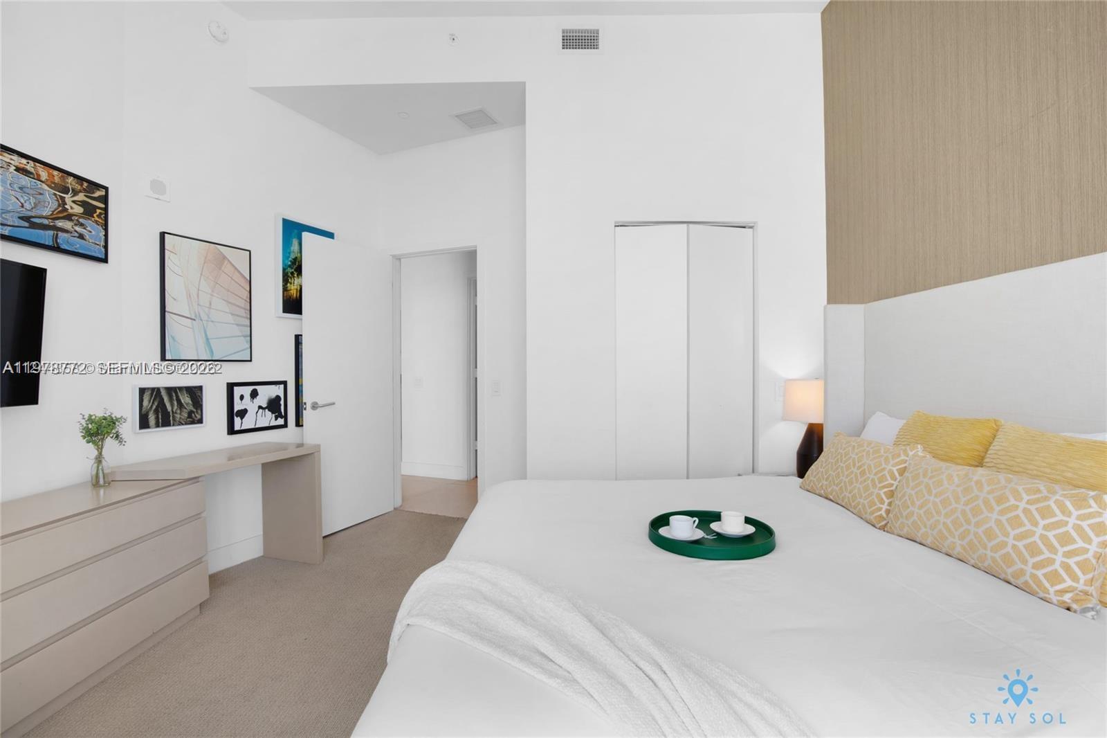 A bedroom features a bed with yellow patterned pillows, a desk, and framed wall art — 4111 S Ocean Dr # 302, Hollywood FL 33019, HOLLYWOOD, FL