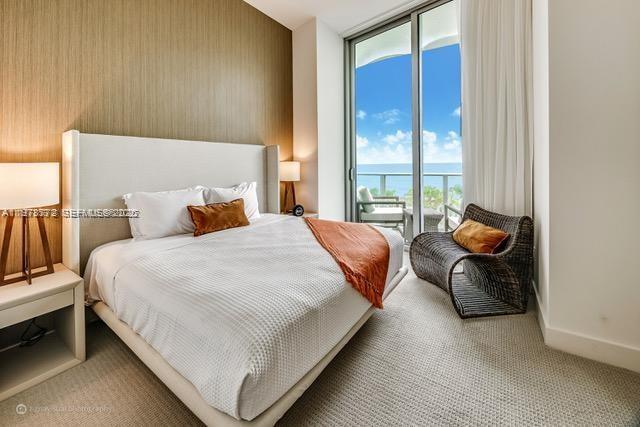 A modern bedroom features a white bed, a wicker chair, and a balcony with ocean views — 4111 S Ocean Dr # 302, Hollywood FL 33019, HOLLYWOOD, FL
