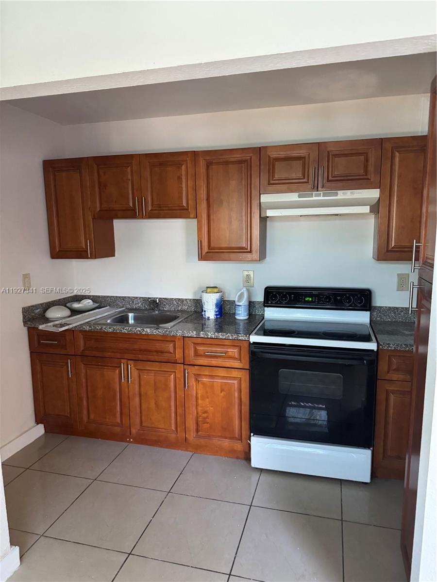 A kitchen features wood cabinets, granite countertops, a stainless steel sink, and a black stove — 4717 SW 33rd Ave # 202, Dania Beach FL 33312, DANIA BEACH, FL