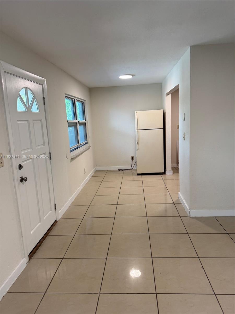 This room features beige tile flooring, a white front door, a window, and a refrigerator — 4717 SW 33rd Ave # 202, Dania Beach FL 33312, DANIA BEACH, FL