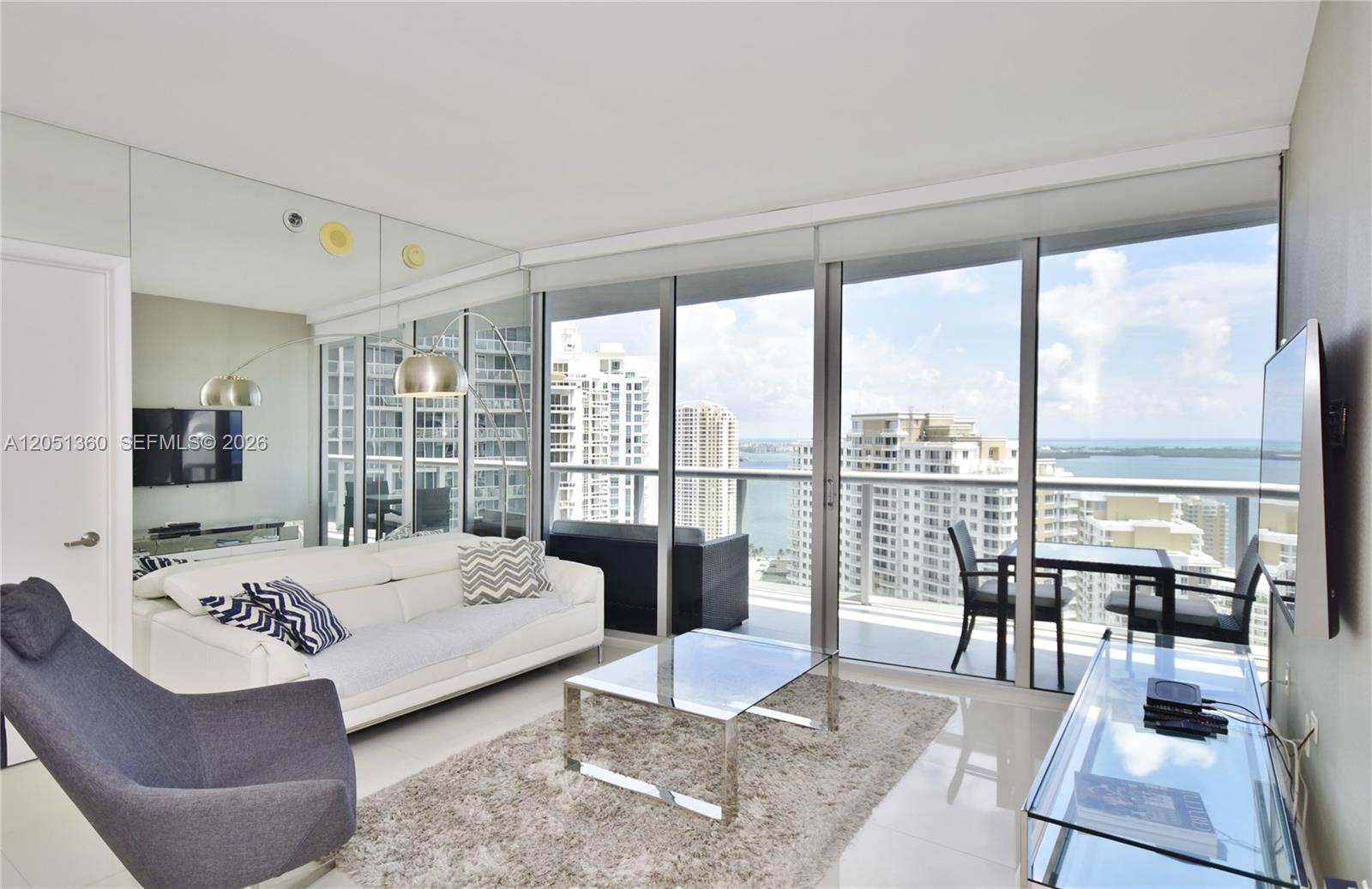 A modern living room features a white sofa, glass coffee table, and floor-to-ceiling balcony windows — 465 BRICKELL AVENUE # 3205, Miami FL 33131, MIAMI, FL