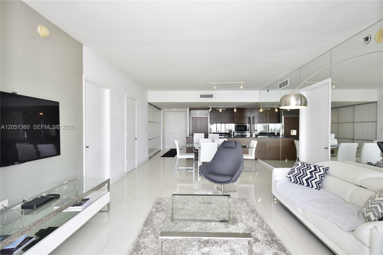 A modern living and dining area features white tile floors, a glass coffee table, and kitchen — 465 BRICKELL AVENUE # 3205, Miami FL 33131, MIAMI, FL