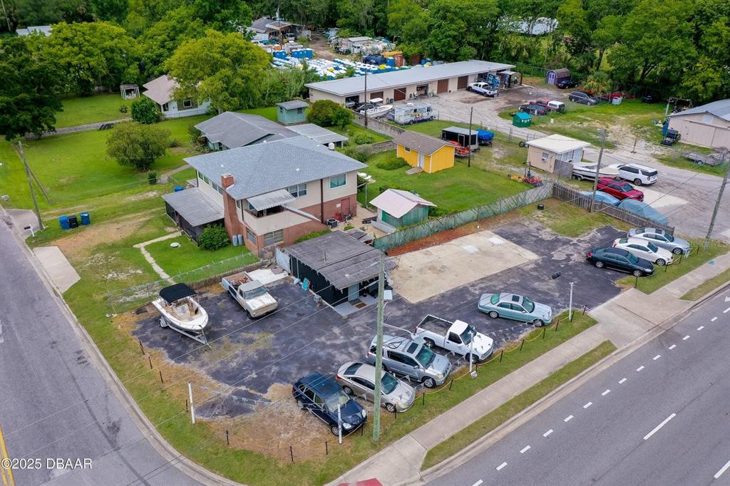 An aerial view shows a multi-story house, a small commercial building, and a paved parking lot — 1520 N NOVA & 10TH ROAD, DAYTONA BEACH, FL