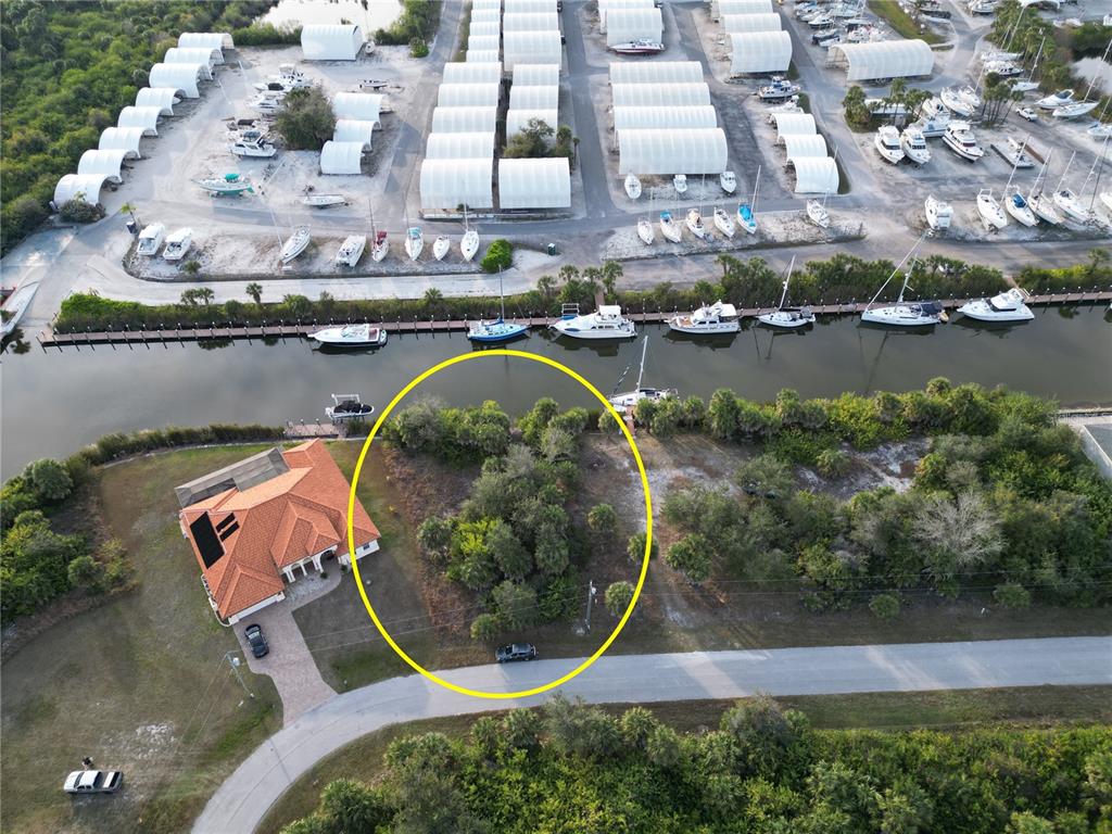 An aerial view shows a vacant, wooded lot next to a house near a canal — 10481 REDONDO STREET, PORT CHARLOTTE, FL