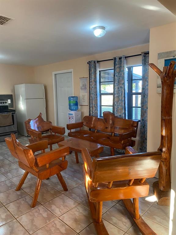 A living room features rustic wooden furniture, tile flooring, and a white refrigerator — 1587 WAYMAN ROAD, MOORE HAVEN, FL