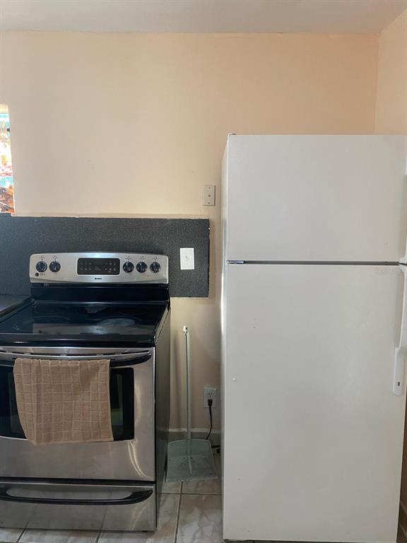 A kitchen features a stainless steel electric range next to a white top-freezer refrigerator — 1587 WAYMAN ROAD, MOORE HAVEN, FL