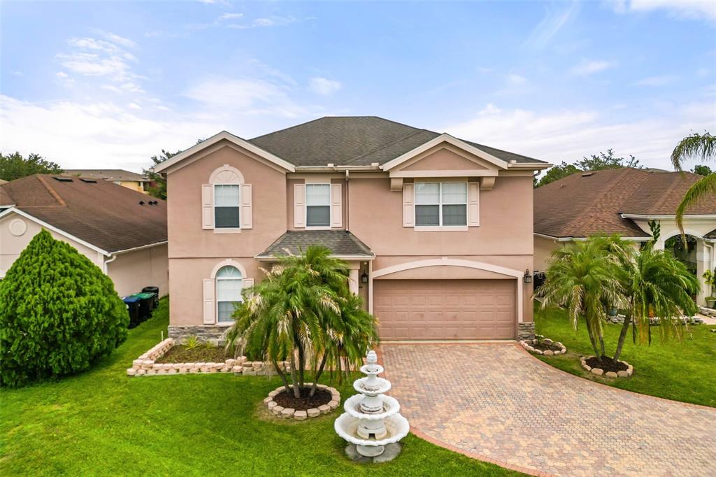 A two-story suburban house with a paved driveway, a fountain, and a two-car garage — 12341 ACCIPITER DRIVE, ORLANDO, FL