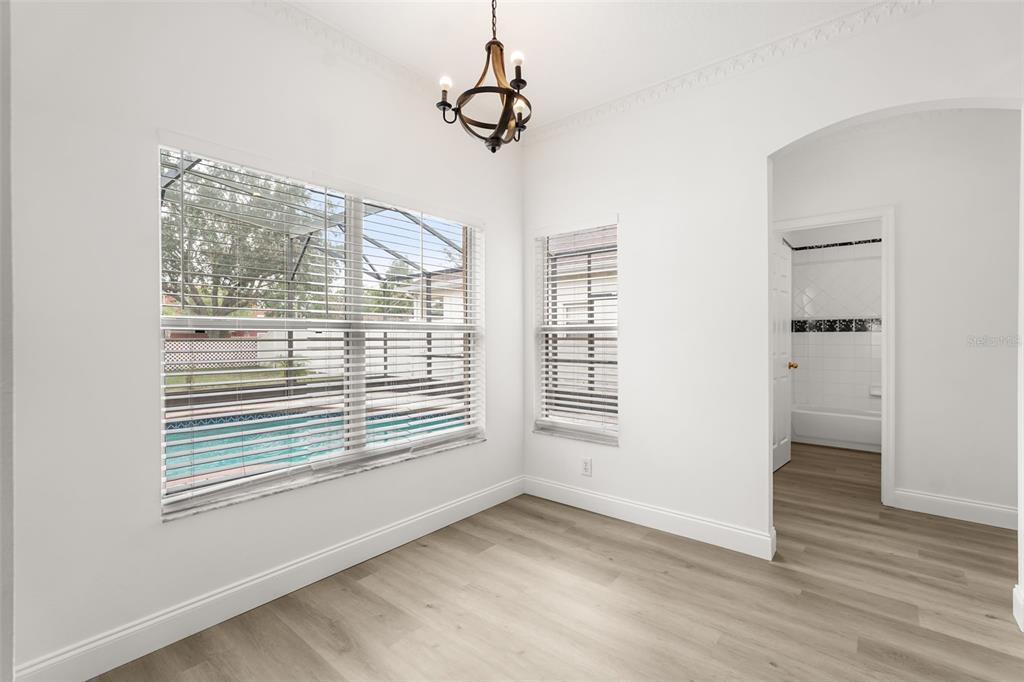 A bright room with light wood-look flooring, a chandelier, and a view of a pool — 12341 ACCIPITER DRIVE, ORLANDO, FL