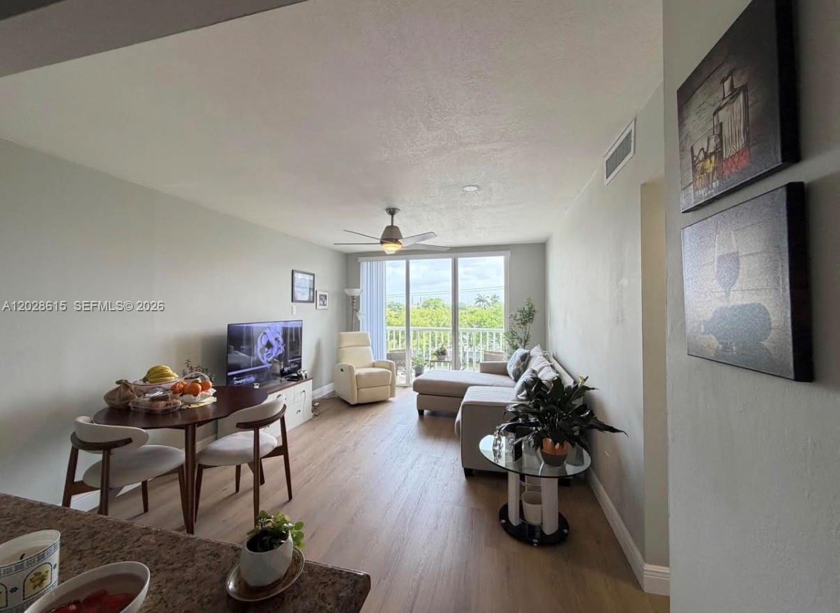 This living and dining area features light wood flooring, a ceiling fan, and balcony access — 3551 SW 9th Ter # 409, Miami FL 33135, MIAMI, FL