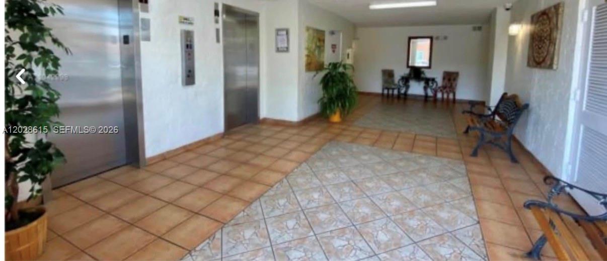 A tiled lobby area features two elevators, a potted plant, and several benches and chairs — 3551 SW 9th Ter # 409, Miami FL 33135, MIAMI, FL