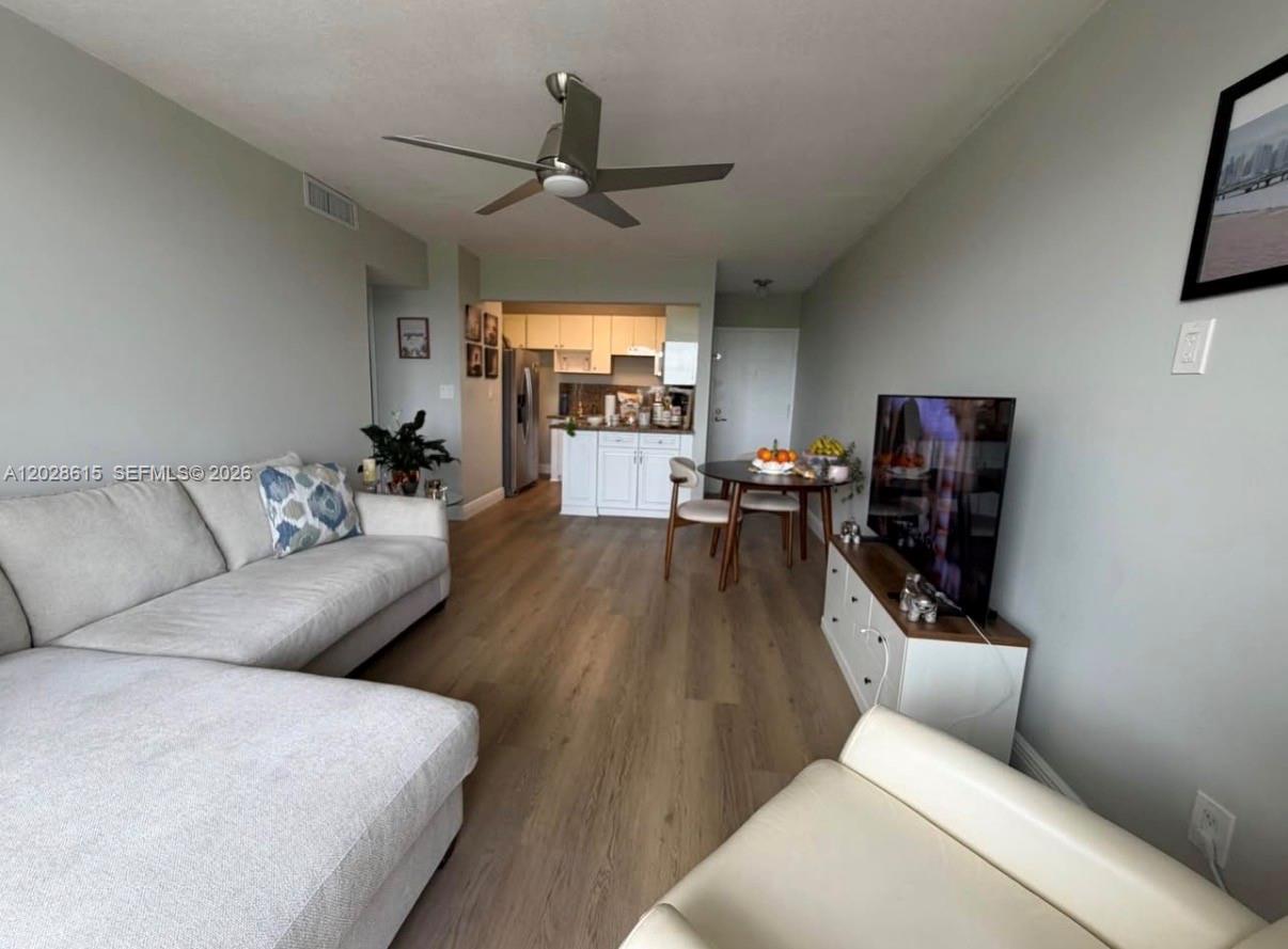 A living room with light wood flooring, a sectional sofa, a television, and a kitchen — 3551 SW 9th Ter # 409, Miami FL 33135, MIAMI, FL