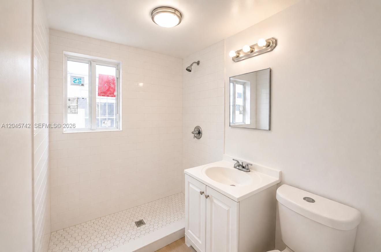A bathroom features a white tiled walk-in shower, a vanity, and a toilet — 7600 Dickens Ave # 2, Miami Beach FL 33141, MIAMI BEACH, FL