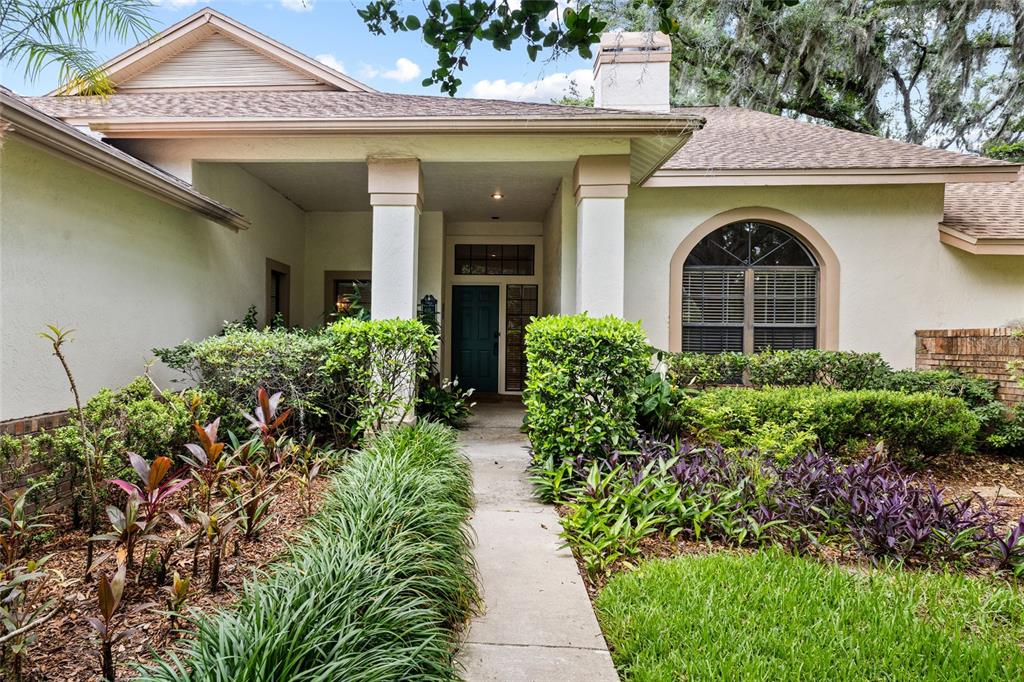 A concrete walkway leads to the covered front entrance of a single-story stucco home — 2555 MASON OAKS DRIVE, VALRICO, FL