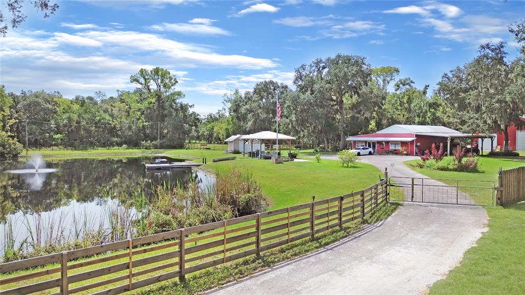 A red building with a metal roof sits beside a pond with a fountain — 2310 DOSTER DRIVE, NEW SMYRNA BEACH, FL