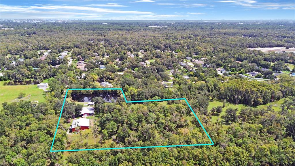 An aerial view shows a red barn and a small pond on a wooded lot — 2310 DOSTER DRIVE, NEW SMYRNA BEACH, FL