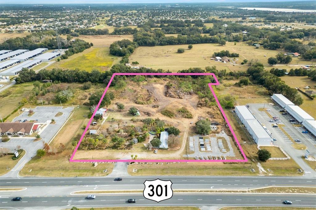 An aerial view shows a vacant lot outlined in pink bordering a multi-lane highway — 10973 N US HIGHWAY 301, OXFORD, FL