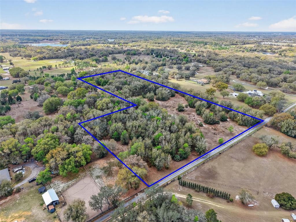 An aerial view shows a wooded plot of land outlined in blue along a road — 3800 DOUBLE D CIRCLE R, LADY LAKE, FL