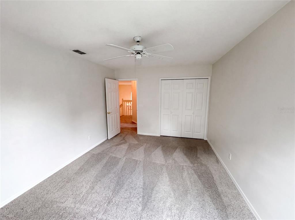An empty bedroom features gray carpet, white walls, a ceiling fan, and a closet — 1379 HAMPSTEAD TERRACE, OVIEDO, FL