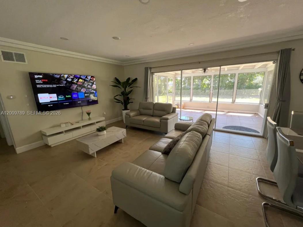 A living room with light tile floors, a large television, and a sliding glass door — 5221 York Ct # 0, Cape Coral FL 33904, CAPE CORAL, FL