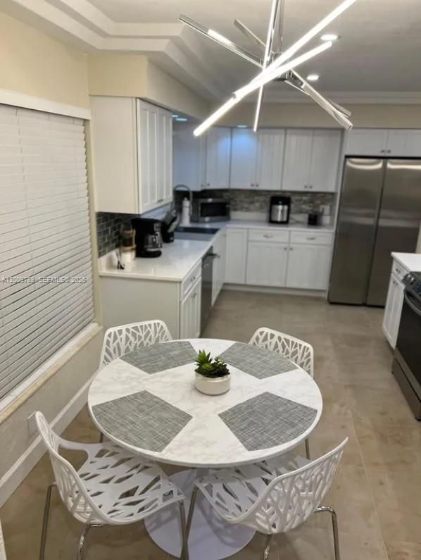 A kitchen features white cabinetry, stainless steel appliances, and a round dining table with chairs — 5221 York Ct # 0, Cape Coral FL 33904, CAPE CORAL, FL