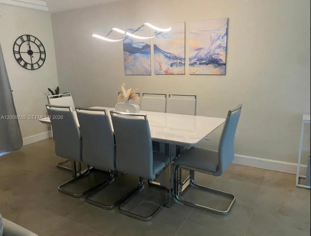 A dining room features a white table, six gray chairs, wall art, and a modern light — 5221 York Ct # 0, Cape Coral FL 33904, CAPE CORAL, FL