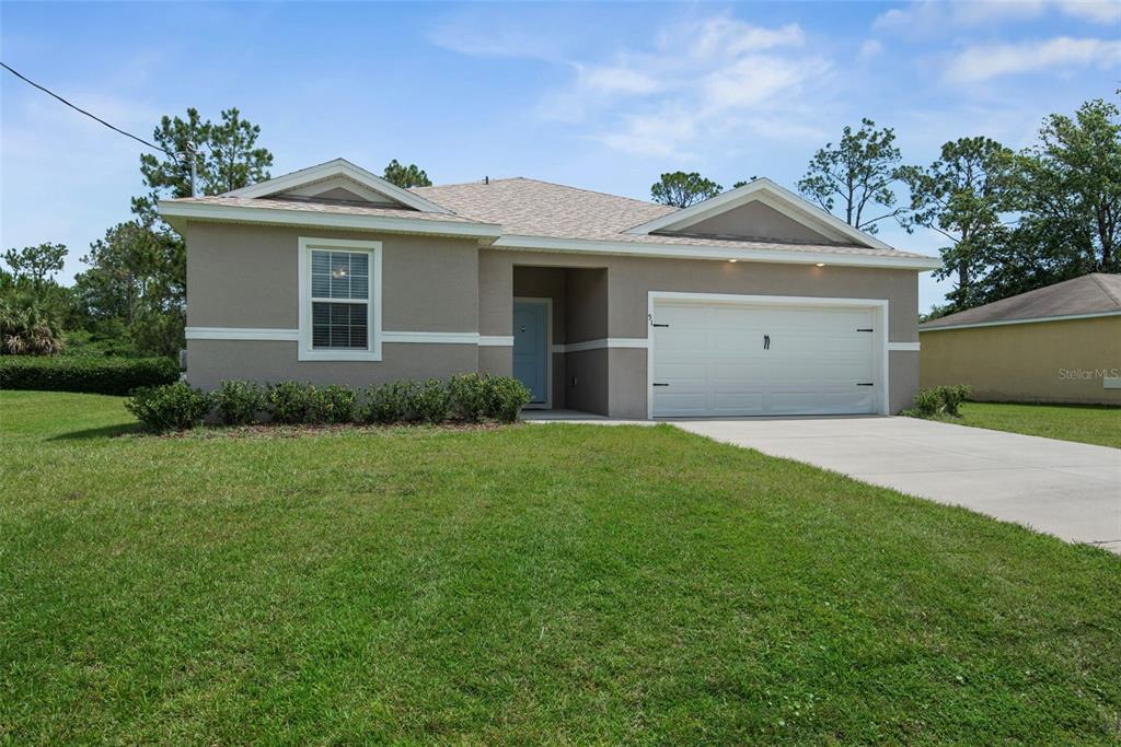 A single-story house with a beige stucco exterior, a two-car garage, and a front lawn — 51 ROYAL OAK DRIVE, PALM COAST, FL