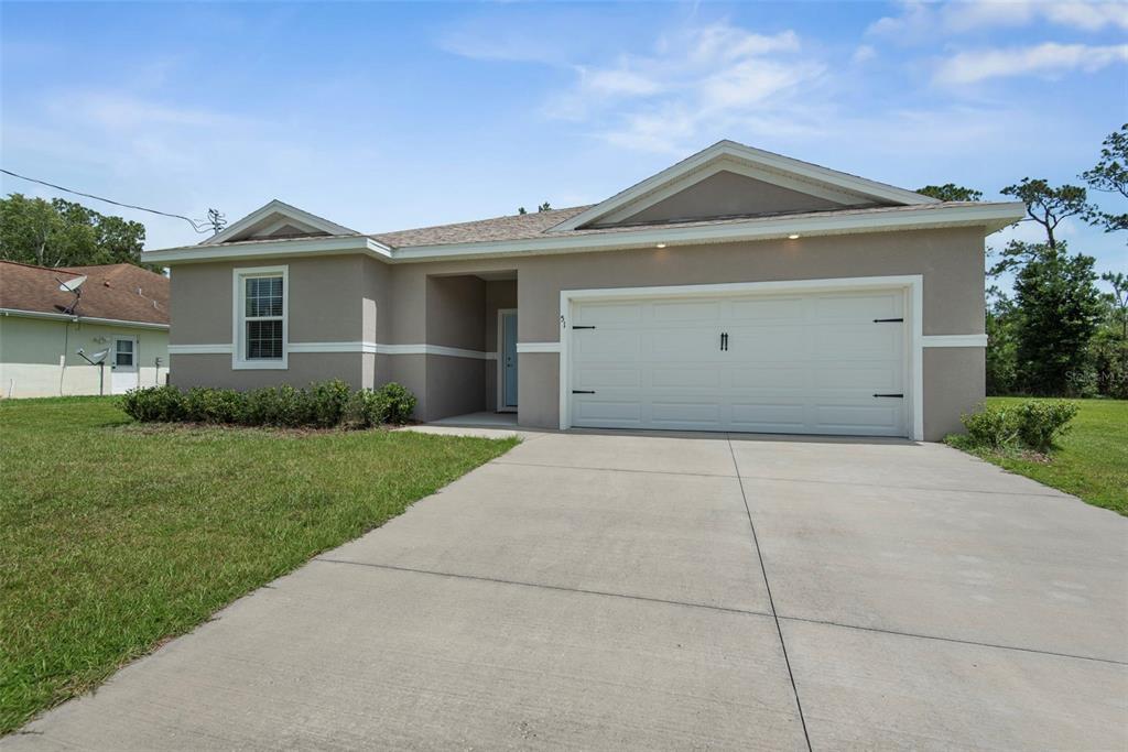 A single-story house with a beige stucco exterior, a two-car garage, and a concrete driveway — 51 ROYAL OAK DRIVE, PALM COAST, FL
