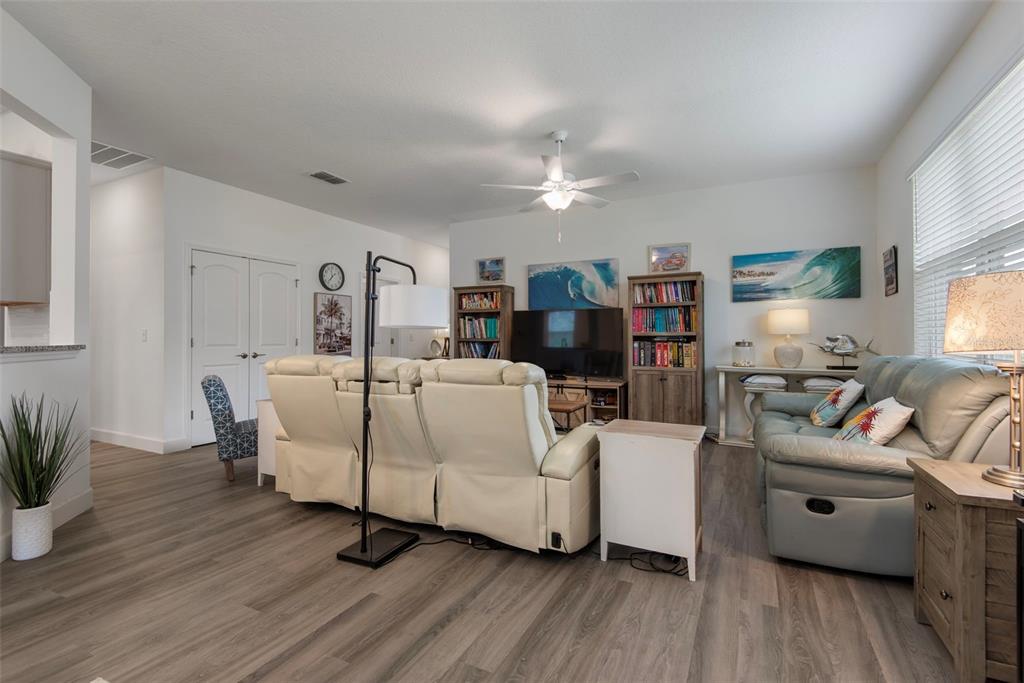 A living room features light wood-look flooring, a white reclining sofa, and a blue sofa — 51 ROYAL OAK DRIVE, PALM COAST, FL