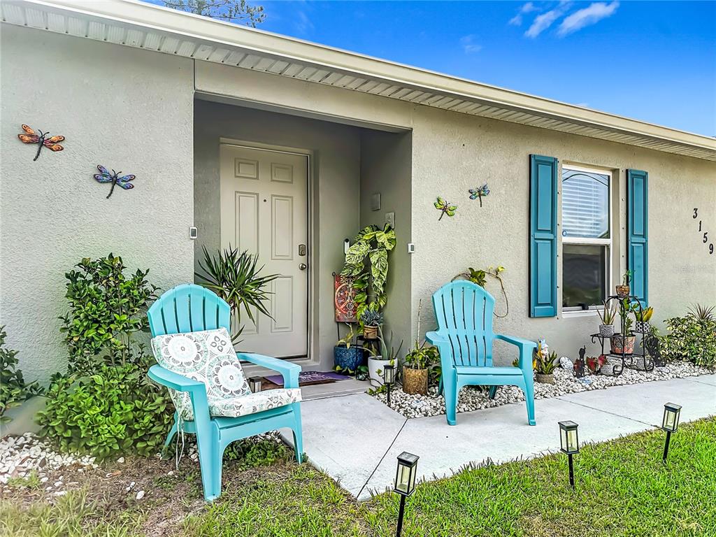 The exterior of a house features a front porch with two blue chairs and dragonfly decorations — 3159 ASPEN ROAD, PALM BAY, FL