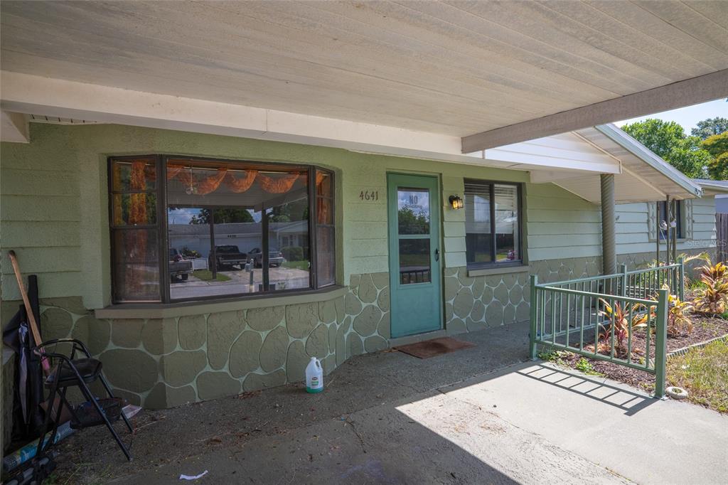 The exterior of a house features a green facade, a bay window, and a covered porch — 4641 AEGEAN AVENUE, HOLIDAY, FL