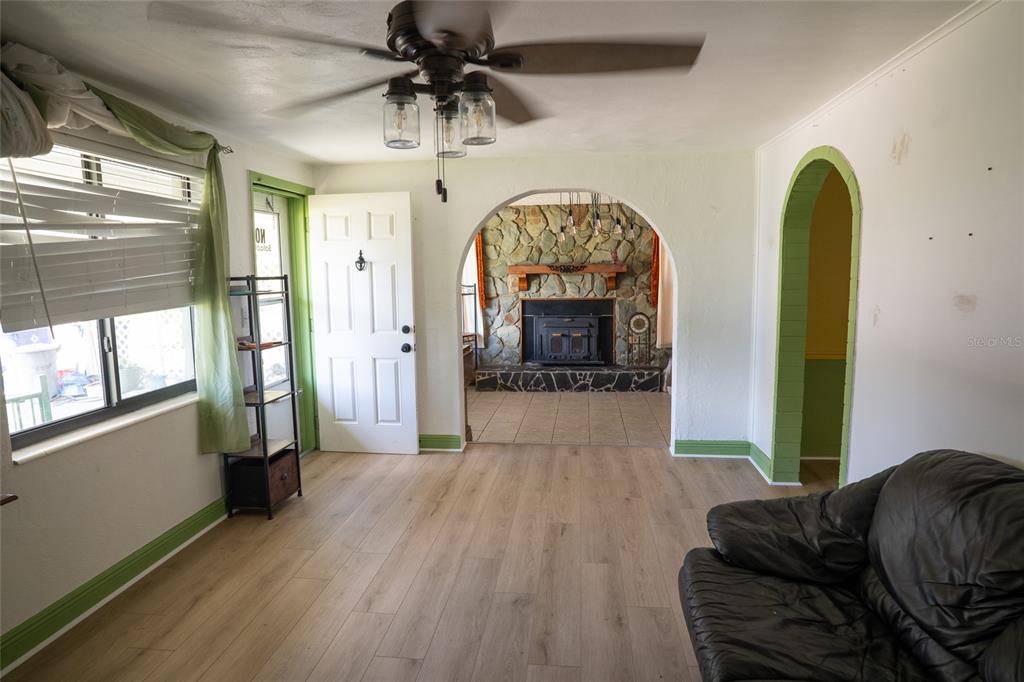A living room features light wood flooring, an arched entryway, and a stone fireplace — 4641 AEGEAN AVENUE, HOLIDAY, FL