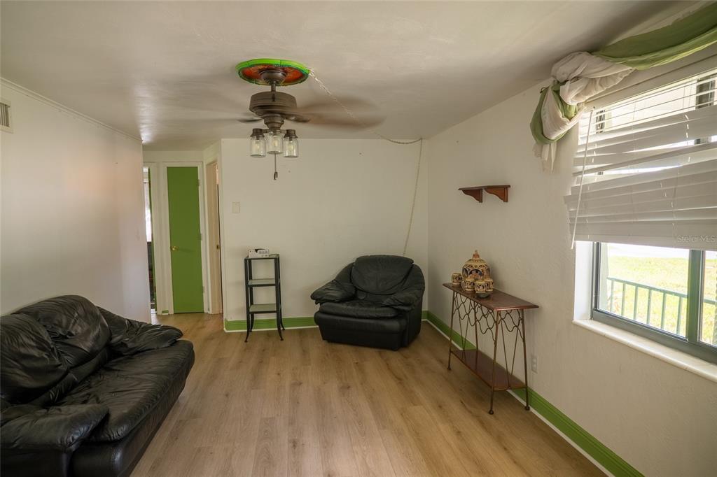 A living room with light wood flooring, a ceiling fan, and black leather furniture — 4641 AEGEAN AVENUE, HOLIDAY, FL