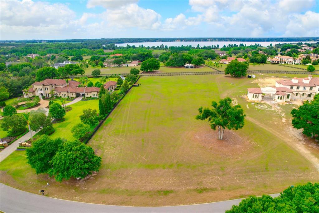An aerial view shows a vacant grassy lot situated between two large residential estates — 10620 BROADLAND PASS LOT 144, THONOTOSASSA, FL