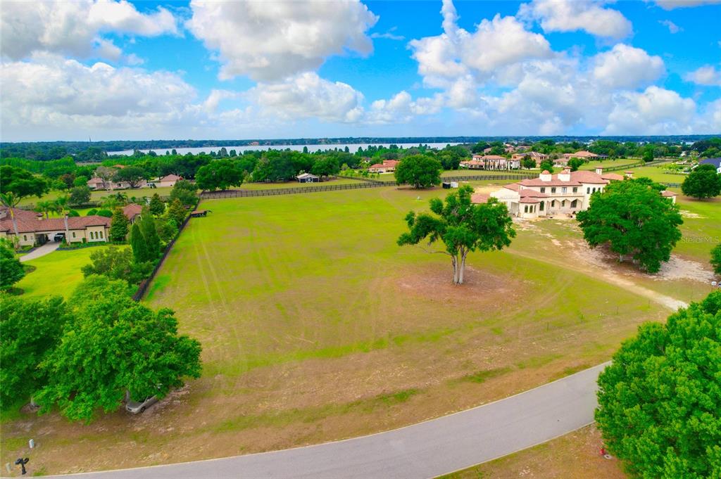 An aerial view shows a large, grassy lot with a house and scattered trees — 10620 BROADLAND PASS LOT 144, THONOTOSASSA, FL