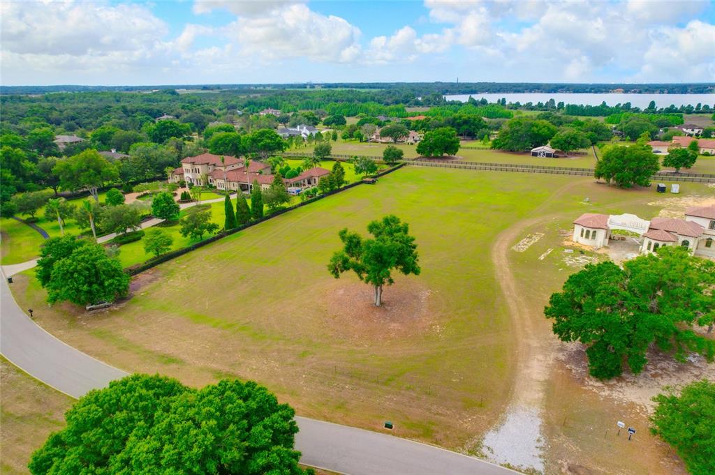 An aerial view shows a large, grassy vacant lot with a single tree and surrounding houses — 10620 BROADLAND PASS LOT 144, THONOTOSASSA, FL