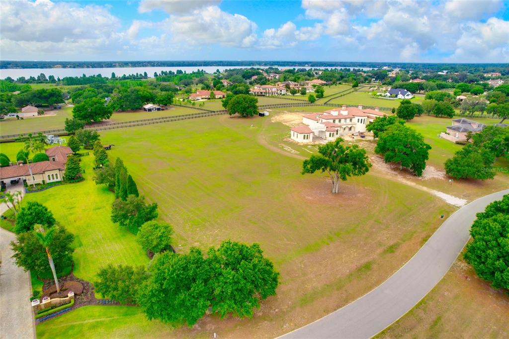 An aerial view shows a large grassy lot with a house and scattered trees — 10620 BROADLAND PASS LOT 144, THONOTOSASSA, FL