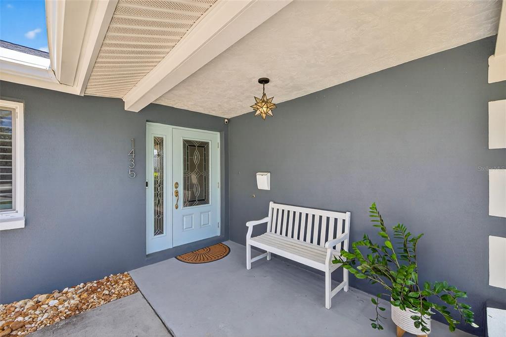 A covered entryway features a light blue front door, a white bench, and a star-shaped light — 1435 48TH AVENUE NE, ST PETERSBURG, FL