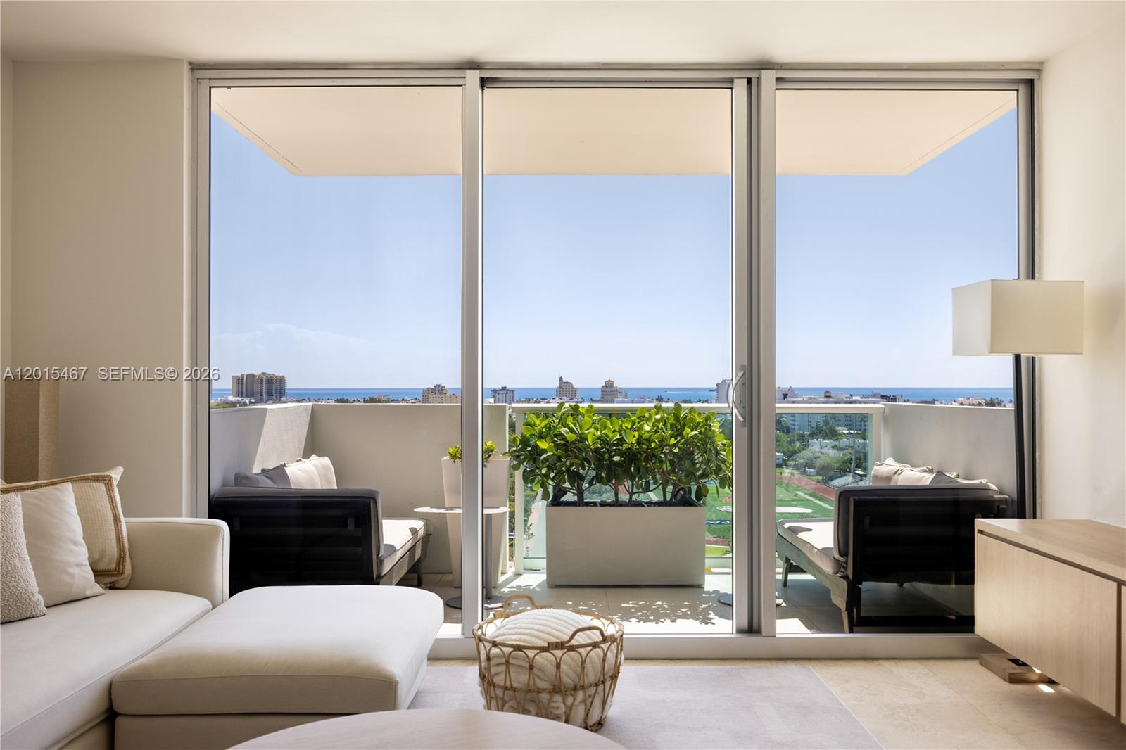 A living room with a white sectional sofa opens to a balcony overlooking the ocean — 1200 West Ave # 1410, Miami Beach FL 33139, MIAMI BEACH, FL