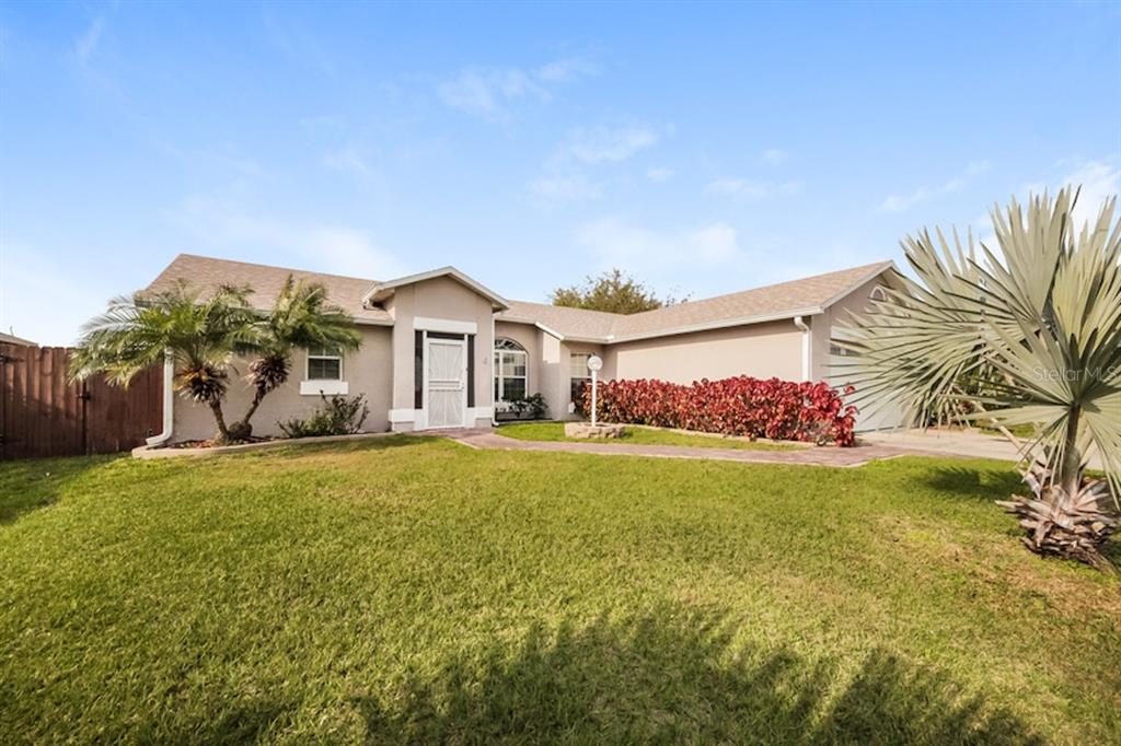 A single-story house with a beige exterior, a front lawn, and a paved walkway — 637 REGENCY WAY, KISSIMMEE, FL