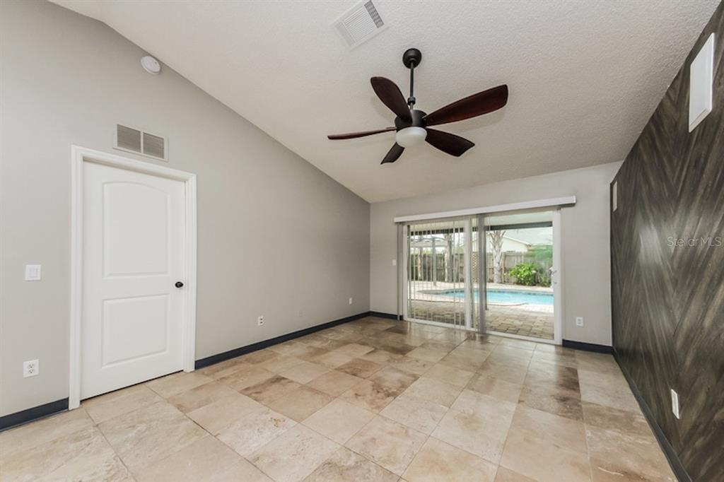 A room with tile flooring, a ceiling fan, and sliding glass doors opening to a pool — 637 REGENCY WAY, KISSIMMEE, FL