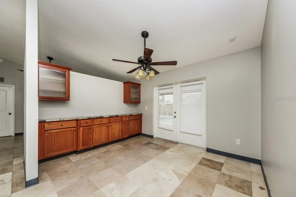 A room with tile flooring, wooden cabinets, a ceiling fan, and glass doors — 637 REGENCY WAY, KISSIMMEE, FL