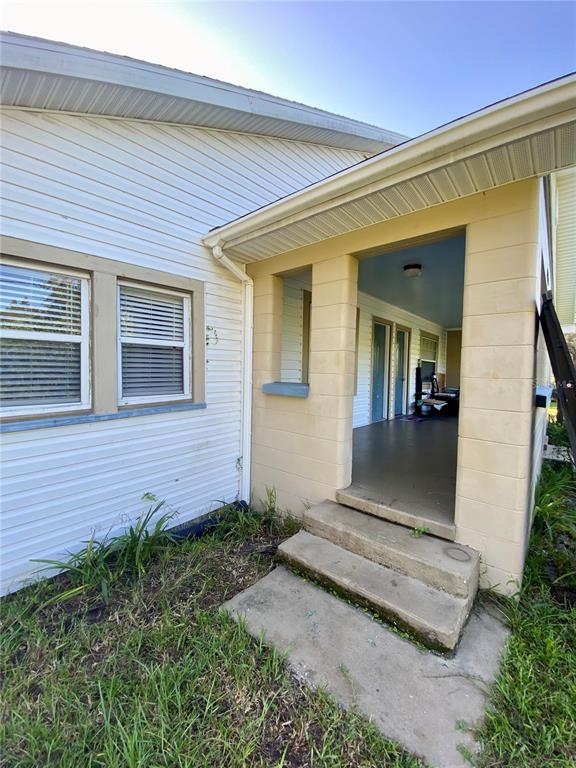 A white-sided house features a covered porch with concrete steps and tan block pillars — 13650 5TH STREET, DADE CITY, FL