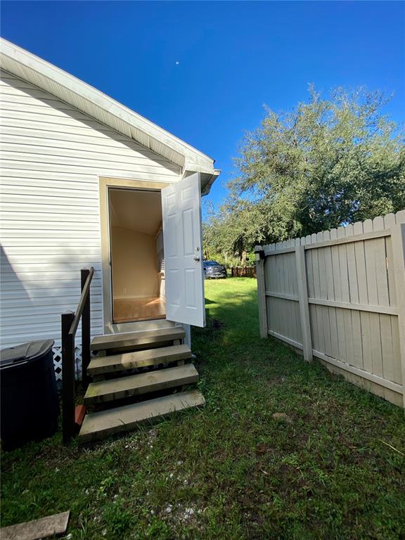 An exterior view of a house with white siding, wooden steps, and an open door — 13650 5TH STREET, DADE CITY, FL