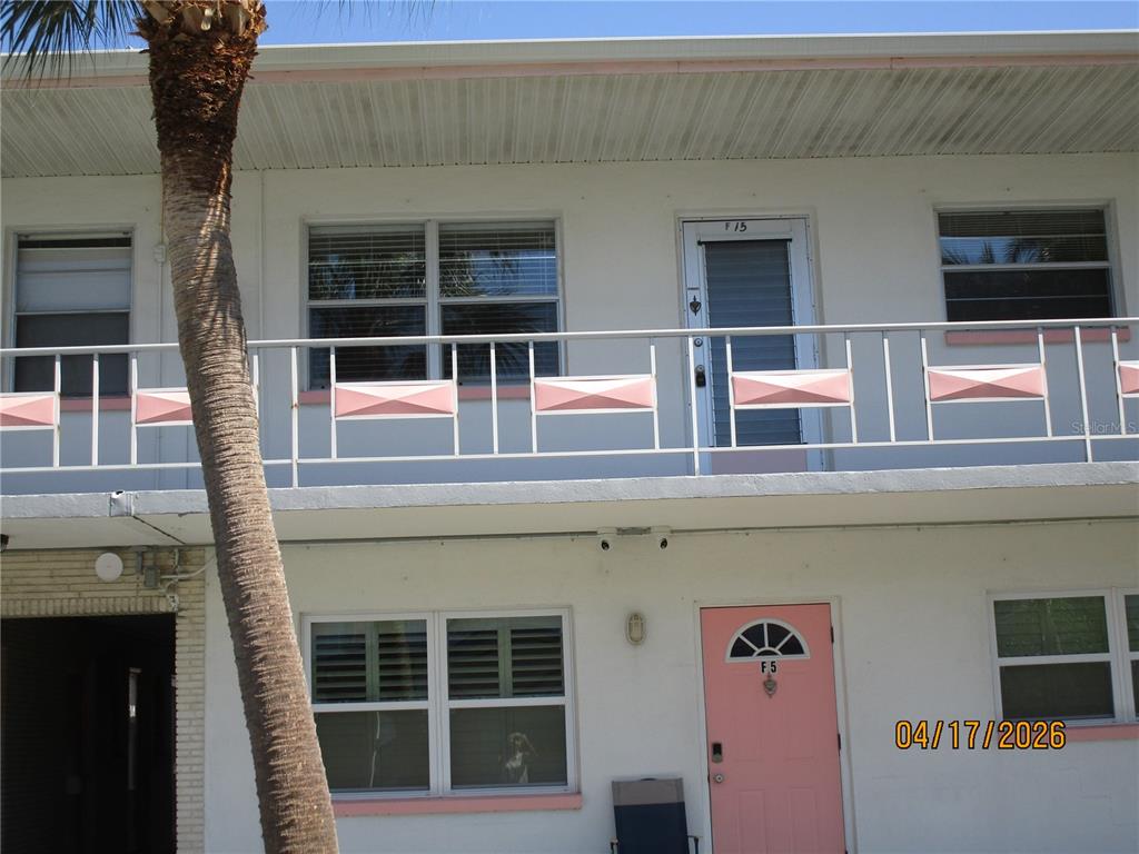 A two-story apartment building exterior features a pink front door and a white metal balcony — 5900 21ST STREET N UNIT 15, ST PETERSBURG, FL