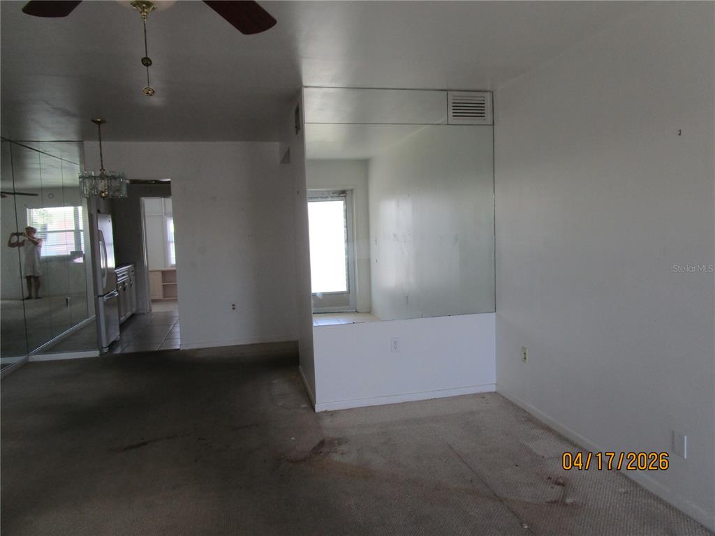 A living area features beige carpeting, mirrored walls, and a doorway leading to a kitchen — 5900 21ST STREET N UNIT 15, ST PETERSBURG, FL