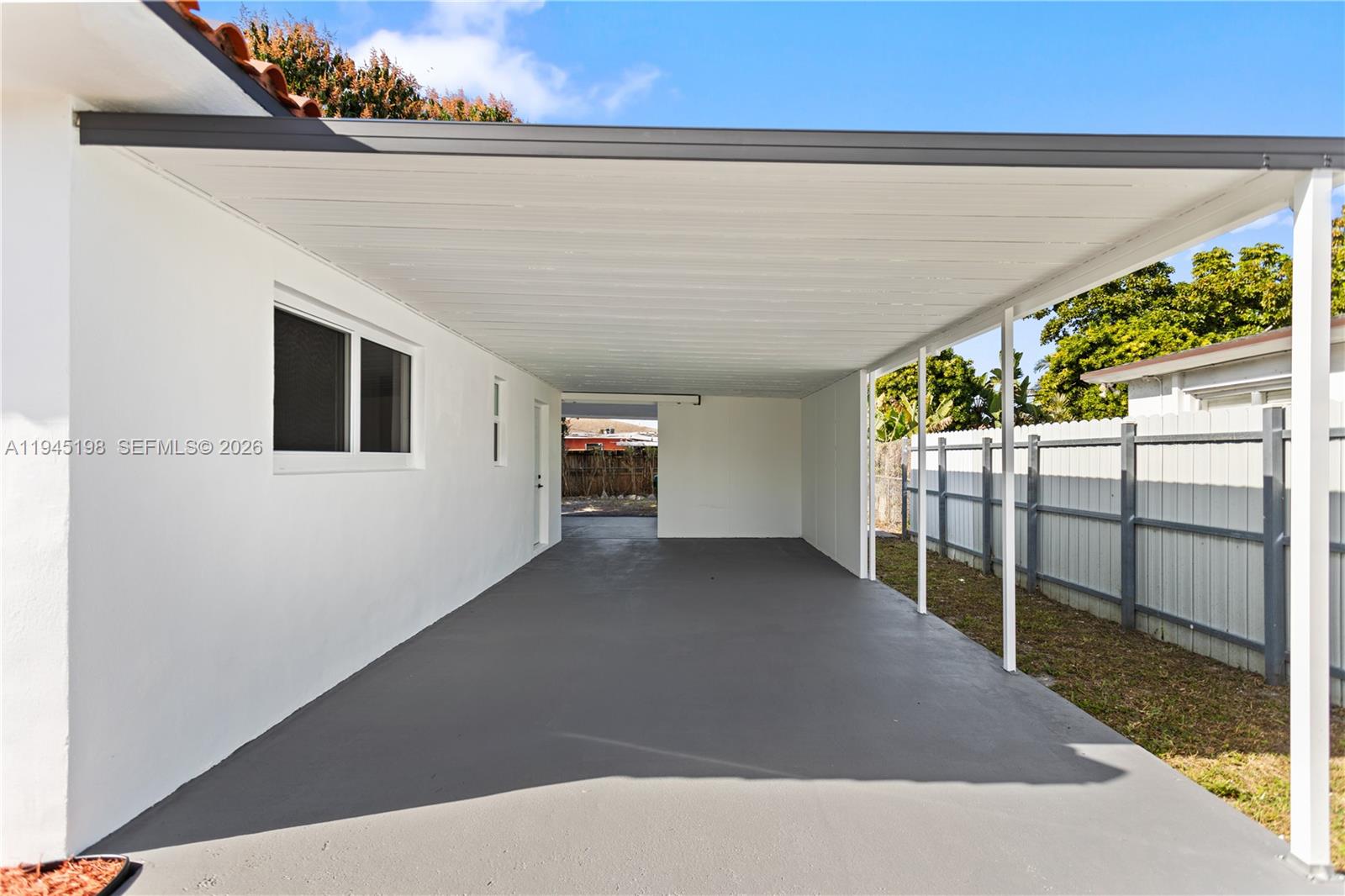 A covered carport with a gray concrete floor, white walls, and a metal roof — 13310 NW 17th Pl, Miami FL 33167, MIAMI, FL