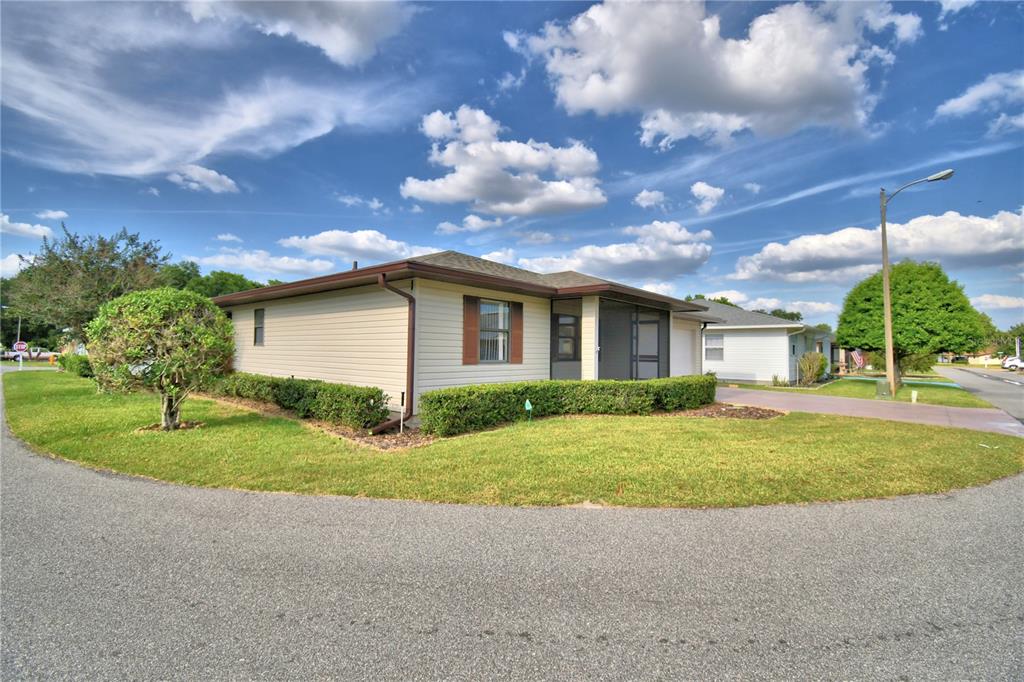 A single-story house with beige siding and a screened-in porch sits on a corner lot — 4828 SQUIRE HOLLOW DRIVE, LAKELAND, FL