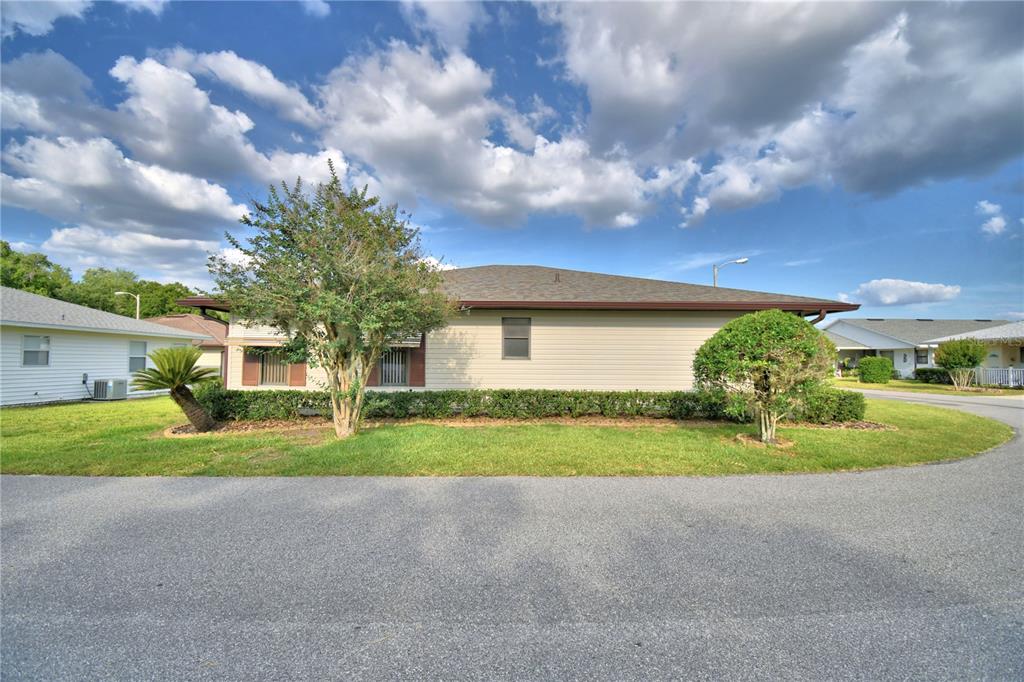 A single-story house with beige siding and a hip roof sits behind a grassy lawn — 4828 SQUIRE HOLLOW DRIVE, LAKELAND, FL