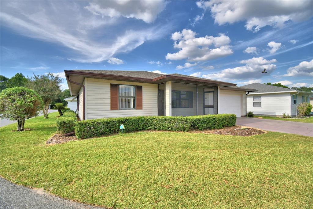 A single-story house with light siding, a screened front porch, and a manicured hedge — 4828 SQUIRE HOLLOW DRIVE, LAKELAND, FL